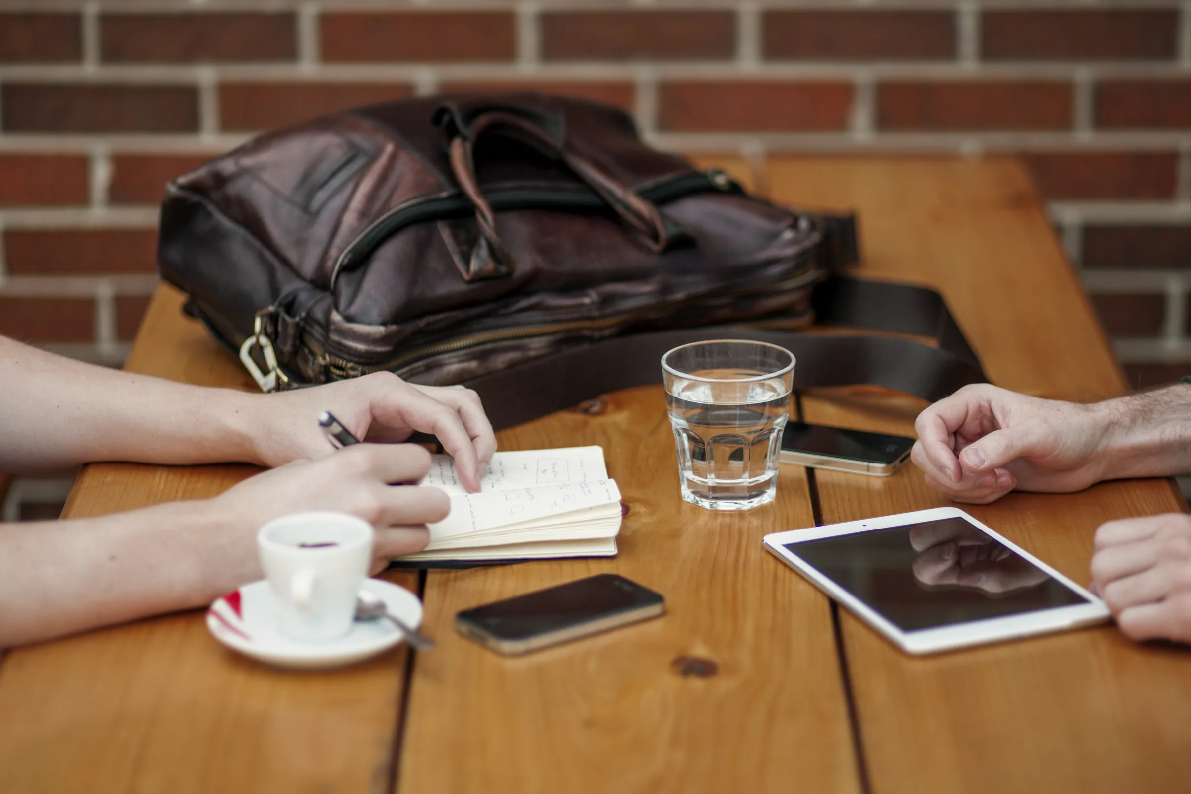 Two people meeting over coffee and notes at a wooden table