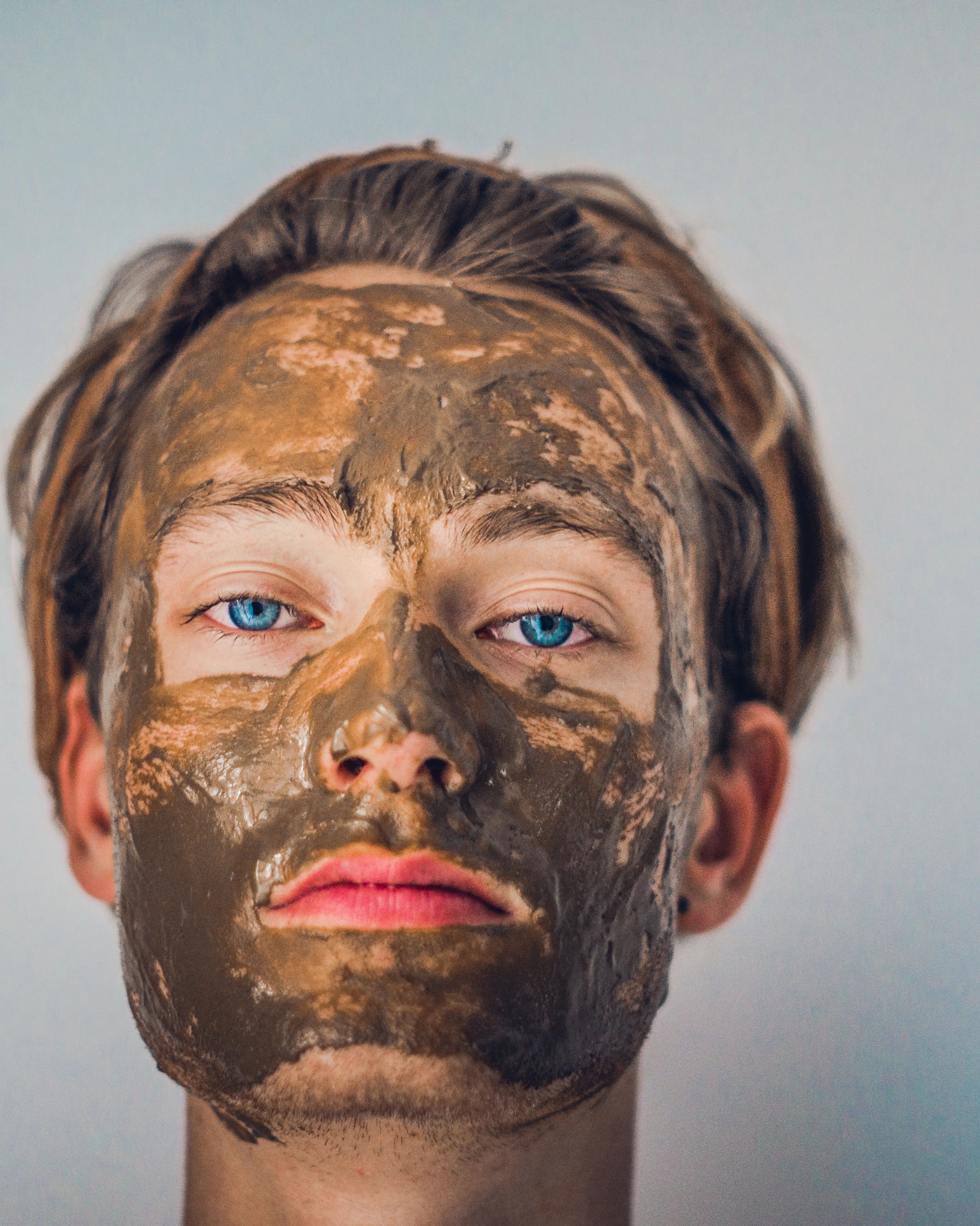 A man wearing a clay face mask during his skincare routine